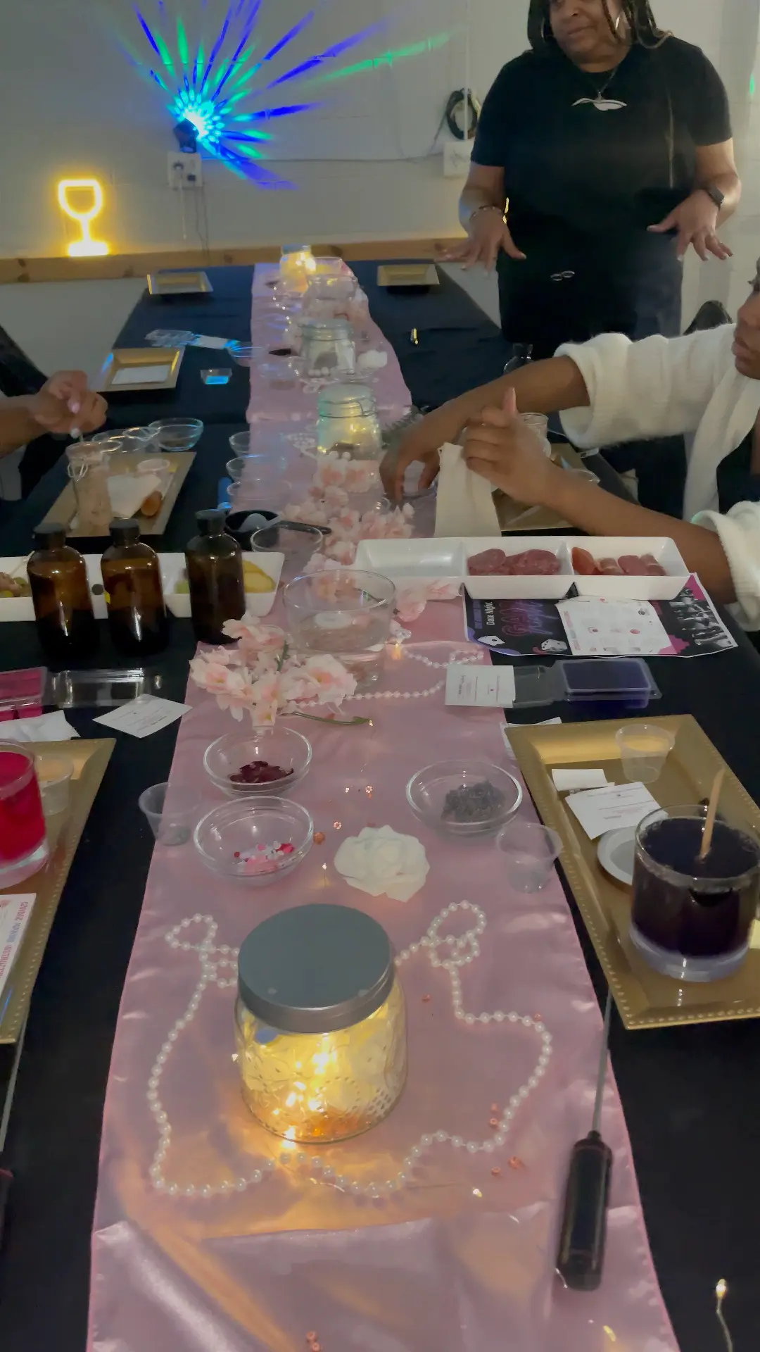 Black table with blush satin runner, pearls, florals and candle blending stations